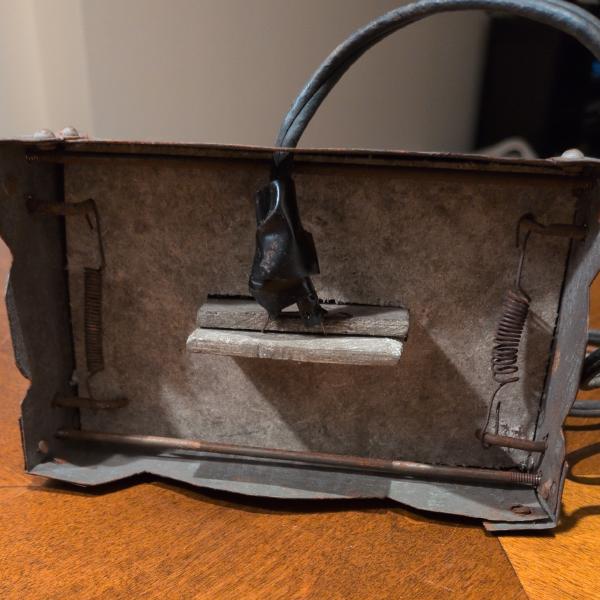 A LOT of action is visible here. First, the pinching arms are bent at 90 degree angles, the creator intended on the springs to perch on the bent portion. The springs also differ from side to side. Perhaps one or both of the original springs had fallen off, which seems very likely. The cord also attaches directly to the heating element wire coming from between two incredibly thick layers of asbestos. It's also possible to note that the rivets keeping the corner pieces affixed did not include space for any kind of soft rubber feet, which would be likely if assembled in a factory.